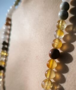 Gros plan sur un Mala porté autour du cou, perles de citrine, cornaline, rhodonite